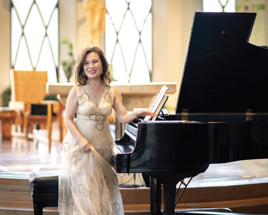Woman in dressstanding at piano, about to play